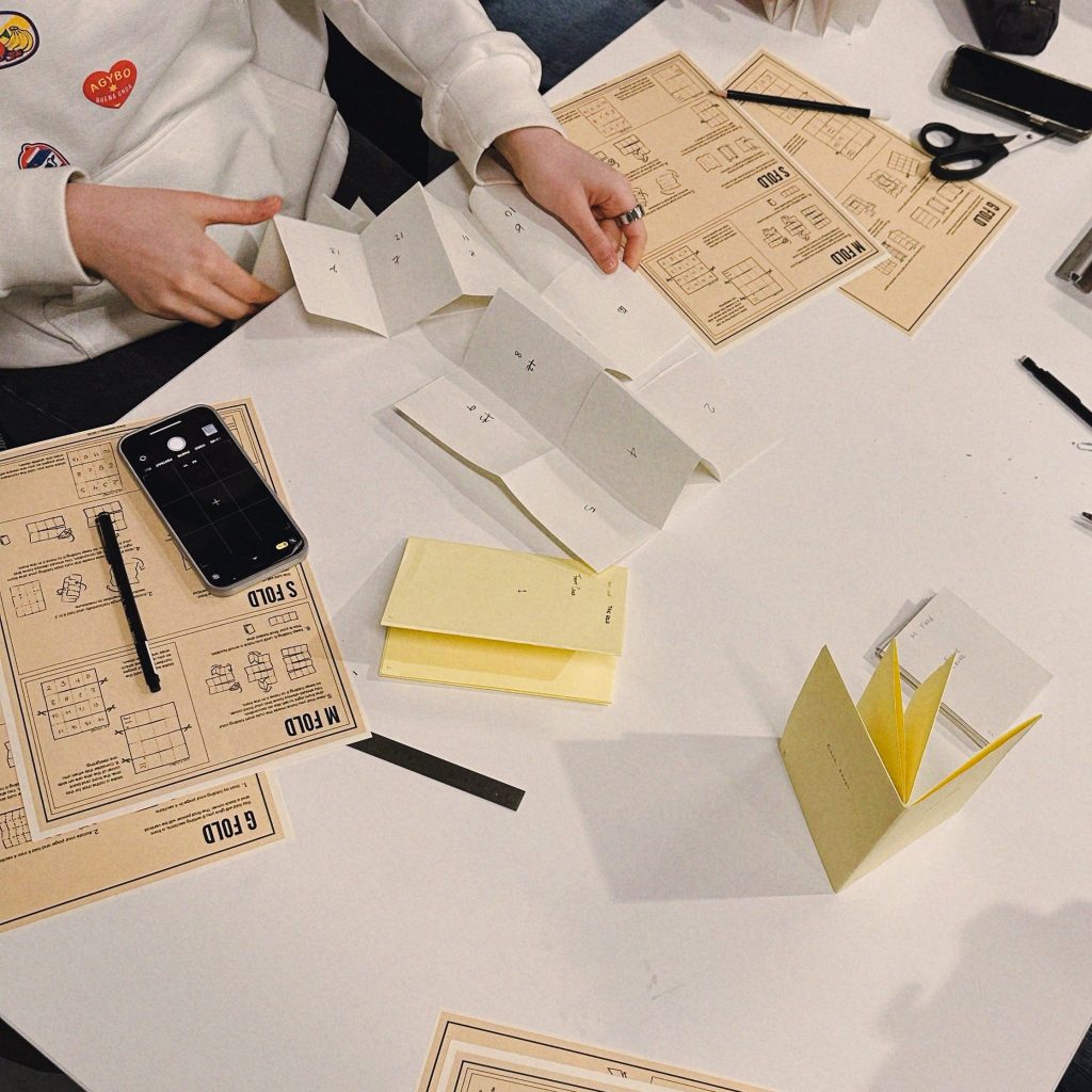 Example of the students with the handouts of the "poster zine workshop"